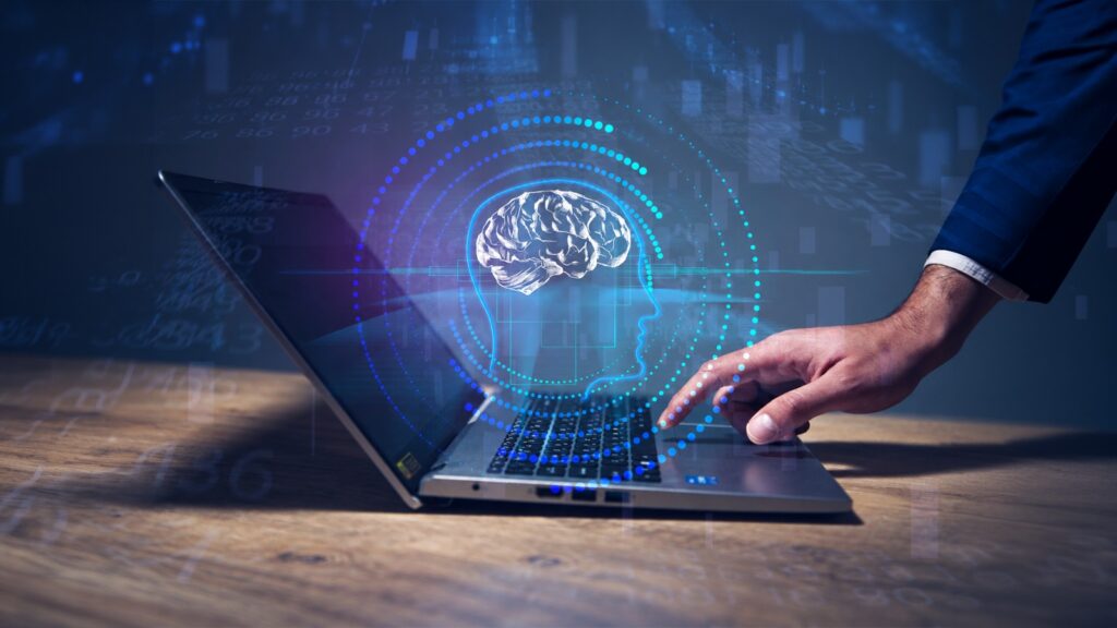 Mão de um homem de terno digitando em um notebook, com a ilustração de um cérebro dentro do perfil de uma cabeça em azul, representando a inteligência artificial