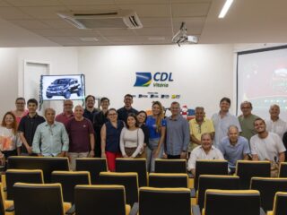 Empresários e equipe da CDL Vitória reunidos na sede da entidade durante o lançamento do Natal Mágico CDL 2026, com o carro zero km do sorteio na TV e a arte da campanha no telão